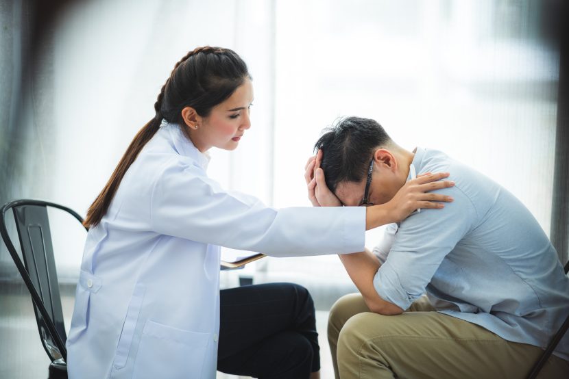 Close-up of psychologist comforting his depressed patient, mental health concept